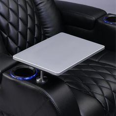 a black leather chair with a silver table and blue lights on the armrests