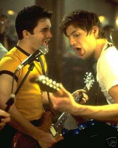 two young men are singing and playing guitars