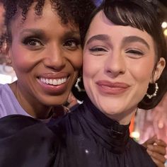 two women pose for the camera with their heads close to one another, both smiling