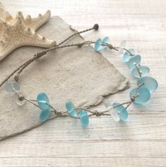 a necklace with blue sea glass beads on a linen piece next to a seashell