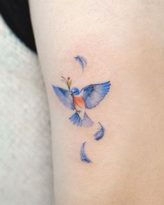 a small blue bird flying through the sky with crescent moon tattoos on it's thigh