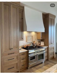 a kitchen with wooden cabinets and stainless steel stove top oven, range hood over an island