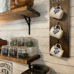 coffee cups and teapots are hanging on the wall next to shelves with signs