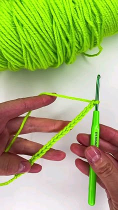 two hands holding a green ball of yarn next to a crochet hook