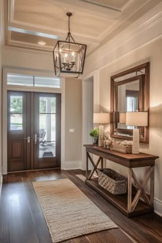 Elegant entryway with wooden doors, console table, mirror, and decorative items. Family Room Entryway Combo, Transitional Entryway Decor, Organized Entryway, Home Entry Way, Mountain House Design, Entryway Table Ideas, Small Entryway Table, Modern Classic Living Room, Foyer Ideas Entryway