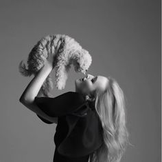 a woman holding a teddy bear up to her face while wearing a black shirt and jeans