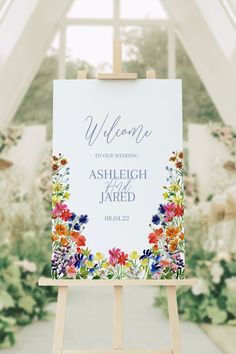 an easel with a welcome sign on it in front of a flowery background