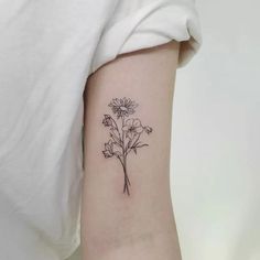 a woman's arm with a small flower tattoo on the back of her left arm