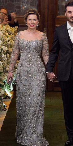 a man and woman in formal wear walking down a hall holding each other's hands