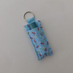 a blue case with flowers on it and a metal keychain attached to it