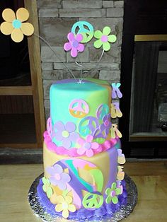 a multi layer cake decorated with flowers and peace signs