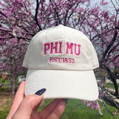 a person holding up a hat with the word phimu in pink letters on it