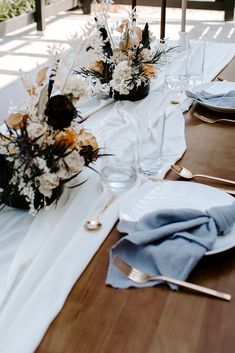 the table is set with flowers and silverware