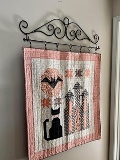 a quilt hanging on the wall next to a door with a coat rack above it