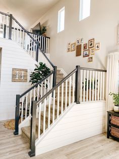 there is a white stair case in the living room with pictures on the wall behind it