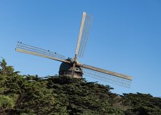 a windmill on top of a hill surrounded by trees