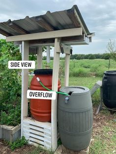 two large barrels sitting next to each other in the grass near a wooden structure with signs on it