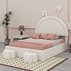 a white bed with pink pillows and bunny ears on the headboard is in a bedroom