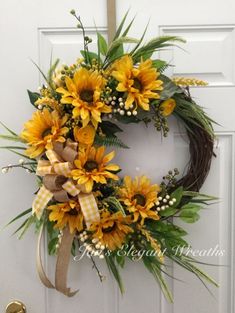 a wreath with sunflowers and baby's breath is hanging on the front door