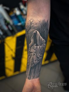 a man's arm with a black and white tattoo of a person holding a cross