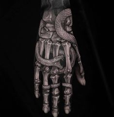 a hand that has a snake on it and bones in the middle, with an arm tattoo