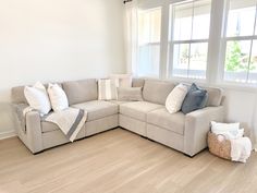 a living room with a sectional couch and pillows on the floor next to a window