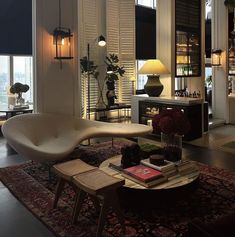 a living room filled with furniture next to a window covered in blinds and bookshelves