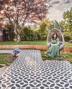 a woman is sitting in a swing chair on the patio with her arms crossed and legs crossed