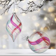 two glass ornaments hanging from a tree branch