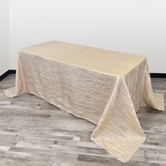 a table with a beige cloth on it in front of a white wall and wooden floor