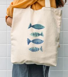 a person holding a tote bag with fish on it