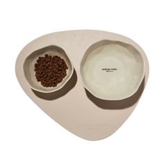 two white bowls with brown dog food in them