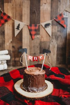 a chocolate cake sitting on top of a wooden table next to a red and black checkered blanket