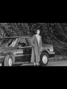 a woman standing next to a parked car