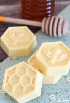 two wax blocks sitting on top of a wooden table next to a jar of honey