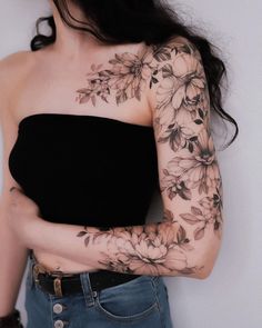 a woman with tattoos on her arm and shoulder is standing in front of a white wall