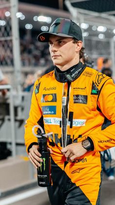 a man in an orange racing suit is holding a water bottle