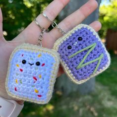 two small crocheted items in the palm of someone's hand, one with a face on it