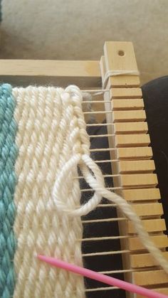 a close up of a weaving machine with yarn on it and a pink needle in the foreground