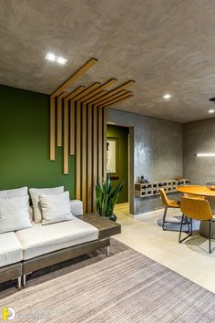 a living room filled with furniture next to a dining table and green accented wall