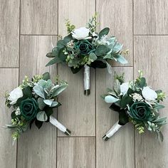 three bridal bouquets sitting on top of a wooden floor