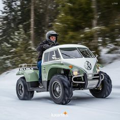 a man riding on the back of a green and white four - wheeled vehicle down a snow covered road