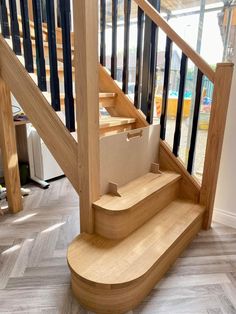 a wooden staircase with black handrails and wood treading on the bottom floor