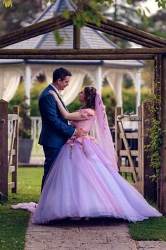 a man and woman dressed in formal wear standing under a gazebo at their wedding