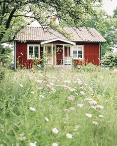 a small red house sitting in the middle of a field