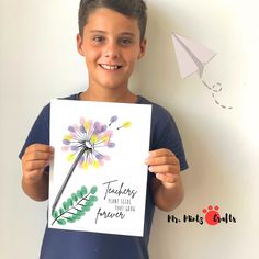 a young boy holding up a card with watercolor flowers on it