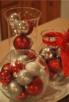 two glass vases filled with ornaments on top of a white table next to a red bow