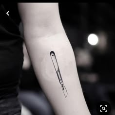 a black and white photo of a medical instrument tattoo on the left inner arm,