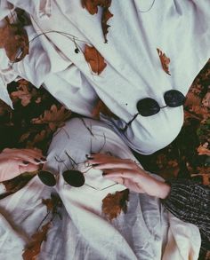 a woman is laying on the ground with her hands on some leaves