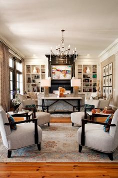 a living room filled with lots of furniture and a chandelier hanging from the ceiling